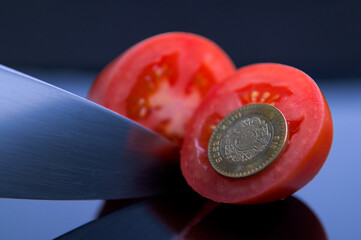 Freshly sliced red tomato in half with a kitchen knife and randomly surrounded by Mexican peso...