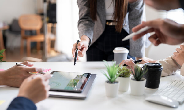 Close-up of businesspeople analyzing ESG data on tablet during meeting, discussing sustainable strategy with teamwork and collaboration in modern office environment.