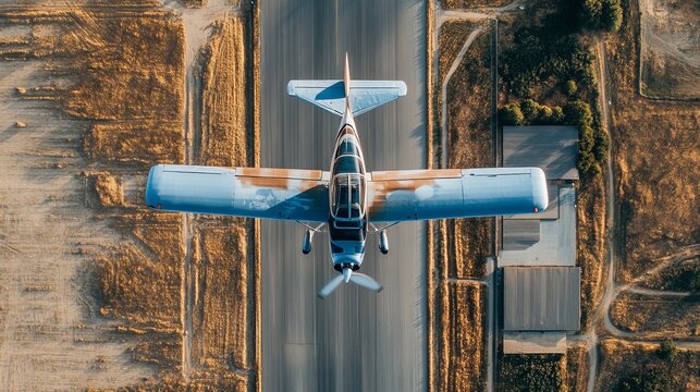 Aerial view of a light aircraft taking off from a runway, surrounded by fields and a small airport