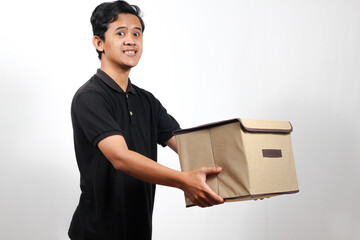 Smiling delivery employee wearing a black polo shirt holding a package box delivering it to the...