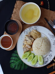 Khao Man Gai — Thai-style Hainanese chicken rice featuring tender boiled chicken served with aromatic chicken oil rice, rich soy-based dipping sauce, and fresh cucumber slices. A beloved Thai comfort 