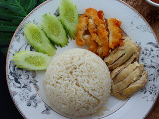 Khao Man Gai — Thai-style Hainanese chicken rice featuring tender boiled chicken served with aromatic chicken oil rice, rich soy-based dipping sauce, and fresh cucumber slices. A beloved Thai comfort 