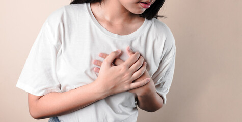heart disease concept. young girl pressing on chest with painful expression. severe heartache and having heart attack or painful cramps.