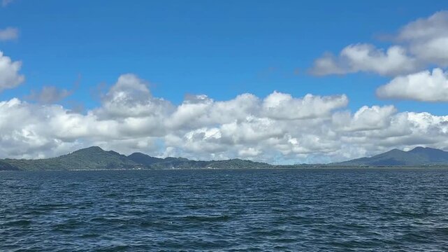 Clean lake water and the sparkling water wave with mountain and hills in the background in Tondano Lake, North Sulawesi, Indonesia.