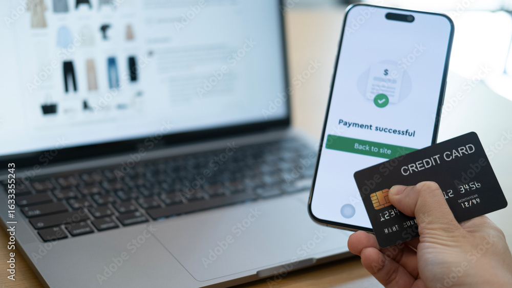 Poster using smartphone to confirm a payment while holding a credit card in front of a laptop, illustrating