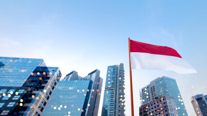 Closeup view of the Indonesian national flag waving with skyscrapers and a blue sky background....