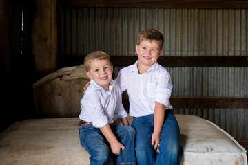 Two country brothers sitting together on wool bales in shearing shed
