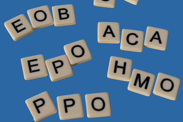 Health insurance or healthcare design element with acronyms on letter tiles. Making sense of common terms. Business or human resources design element isolated on blue.