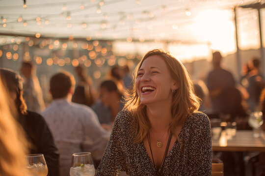 Sunset in a rooftop coworking cafe with jazz music playing softly A woman laughs while networking with others over mocktails The mood is joyful and free