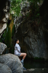 Woman Relaxing by a Rocky Stream in a Tranquil Mountainous Forest