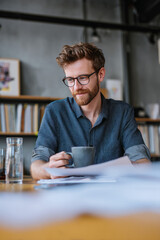 Morning in a quiet coworking library with welcome cards on every desk A man reads the schedule while sipping tea and waiting for the event to start