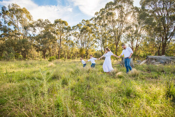 Family of four walking together through lush field in golden afternoon light