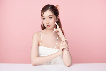 A beautiful young Asian woman with clean, fresh skin against a pink background. Skincare, facial treatment, cosmetology, beauty, and spa. An elegant portrait of an Asian woman.