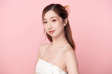 A beautiful young Asian woman with clean, fresh skin against a pink background. Skincare, facial treatment, cosmetology, beauty, and spa. An elegant portrait of an Asian woman.