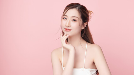 A beautiful young Asian woman with clean, fresh skin against a pink background. Skincare, facial treatment, cosmetology, beauty, and spa. An elegant portrait of an Asian woman.