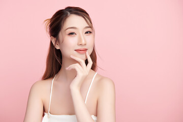 A beautiful young Asian woman with clean, fresh skin against a pink background. Skincare, facial treatment, cosmetology, beauty, and spa. An elegant portrait of an Asian woman.