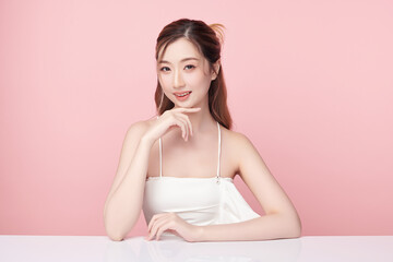 A beautiful young Asian woman with clean, fresh skin against a pink background. Skincare, facial treatment, cosmetology, beauty, and spa. An elegant portrait of an Asian woman.