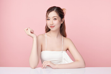A beautiful young Asian woman with clean, fresh skin against a pink background. Skincare, facial treatment, cosmetology, beauty, and spa. An elegant portrait of an Asian woman.