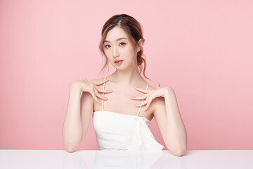 A beautiful young Asian woman with clean, fresh skin against a pink background. Skincare, facial treatment, cosmetology, beauty, and spa. An elegant portrait of an Asian woman.