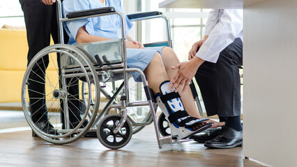 Close up asian doctor physiotherapy check splint leg support to senior old woman patient assisted by caregiver medical orthopedic trauma treatment team providing rehabilitation in a healthcare clinic.