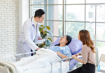 Obraz premium Asian man professional doctor visiting ward, consulting, talking to physician, senior woman patient lying on hospital bed explaining medical treatment with lovely daughter family showing care support.