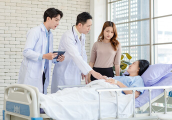 Obraz premium Asian man doctor and medical team visiting ward consulting talking explain medical treatment to lovely daughter family showing healthcare care support while senior woman patient lying on hospital bed.