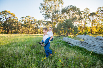 Little boys doing piggy back ride in rural Australian bush setting