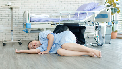 Asian female patient suffering from heart attack accidental fall down from chair lies unconscious on hospital floor elderly woman injury and hurt older people medical emergency physical healthcare.