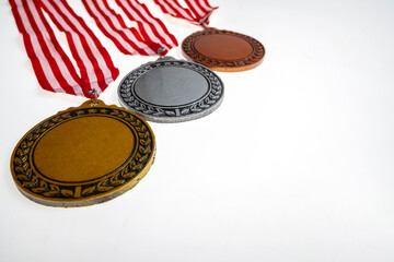 Set of the bronze, silver, and golden award medals suspended from a red and white striped ribbon isolated over a white background. Copy space. Symbol of achievement, recognition, or competition