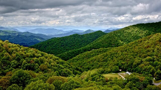 Drone glides through smoky clouds above rain-kissed mountains.