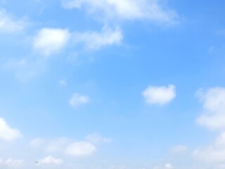 Clear blue sky with soft white clouds. Bright summer sky background. Soft white clouds float in the clear blue sky. Clear blue sky, bright spring, soft sky gradient, wallpaper landscape, aerial view.