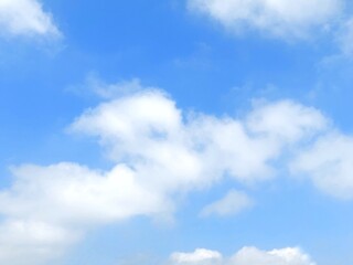 Obraz premium Clear blue sky with soft white clouds. Bright summer sky background. Soft white clouds float in the clear blue sky. Clear blue sky, bright spring, soft sky gradient, wallpaper landscape, aerial view.