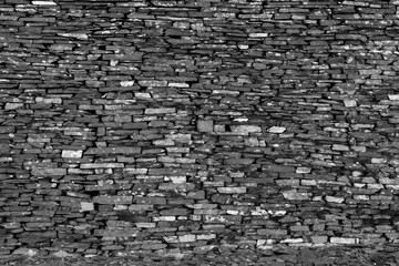 Close-up of dry stone wall with rough slate texture in monochrome