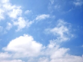 Fototapeta premium Clear blue sky with soft white clouds. Bright summer sky background. Soft white clouds float in the clear blue sky. Clear blue sky, bright spring, soft sky gradient, wallpaper landscape, aerial view.