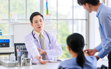 Fototapeta premium Asian professional doctor consulting senior old female patient with caregiver beside in bright medical office checkup insurance attentively reviews health details providing 