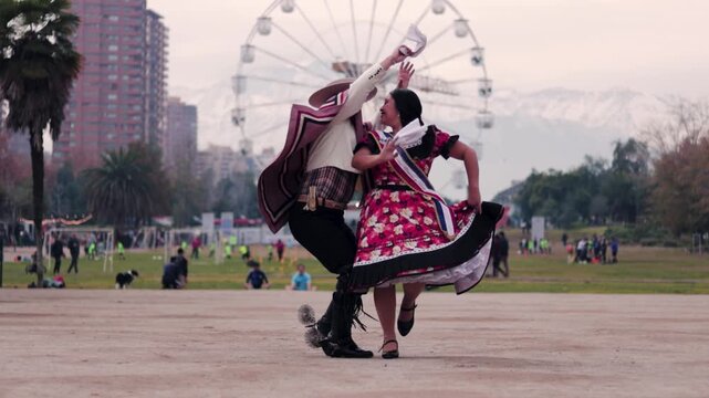 Smiling young couple dressed as Chilean huasos, joyfully dancing cueca outdoors. Traditional Chilean dance. Chilean traditions, celebrations.