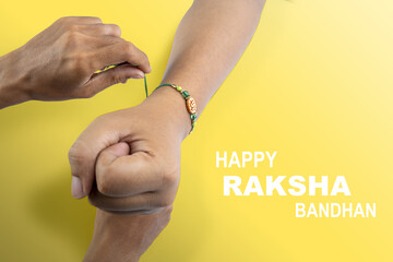 Human hands tying colorful rakhis on the wrist, with a colored background, celebrating the bond of love and protection. Concept of the Raksha Bandhan festival