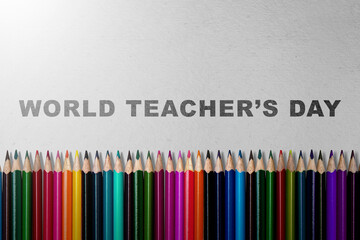 Row of colored pencils with the message of World Teacher Day on a grey background. Concept of World Teacher Day