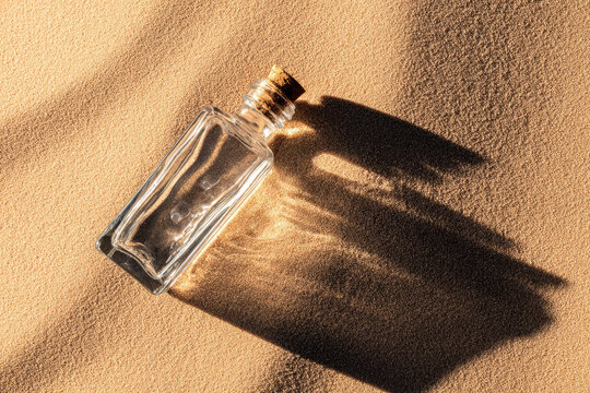 Empty glass bottle with cork casting long shadow on golden desert sand, sunlight creating textured pattern, minimalistic and tranquil scene, concept of isolation and message in bottle