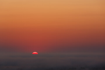 Red Sun Setting Over Foggy Horizon