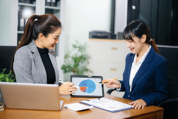 Fototapeta premium Two businesswoman discuss investment project working and planning strategy with tablet laptop computer in modern office.