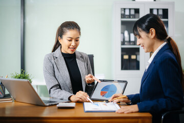 Two businesswoman discuss investment project working and planning strategy with tablet laptop computer in modern office.