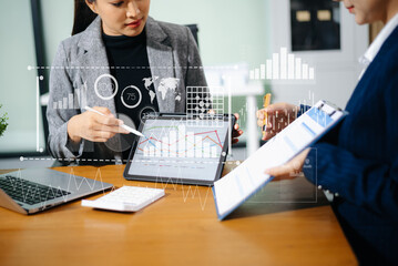 Two businesswomen review financial charts with digital data UI overlays in office. Concept of fintech, big data, global strategy