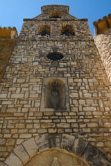 Ancient stone bell tower adorned with religious symbols against a blue sky, showcasing historical architecture and cultural significance.