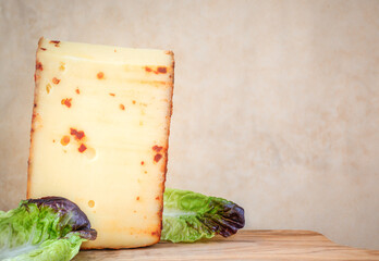 Background with a piece of cheese with red pepper and lettuce leaves