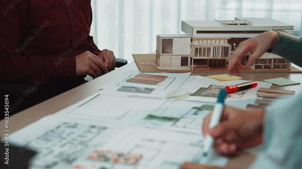 Poster engaged individuals in an architecture studio collaborate on modern design projects, discussing plan
