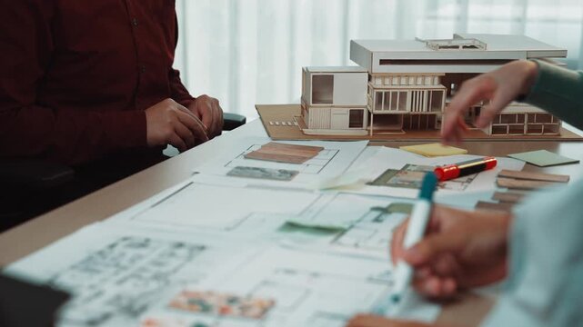 Engaged individuals in an architecture studio collaborate on modern design projects, discussing plans and reviewing models while fostering creativity and innovation. SACTR