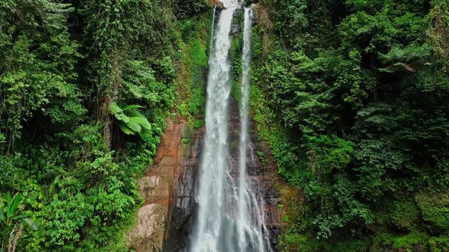 Closer drone view of Gitgit Waterfall in Bali, pouring down between dense green trees and tropical vegetation. A powerful yet peaceful natural scene deep in the island&rsquo;s jungle landscape.