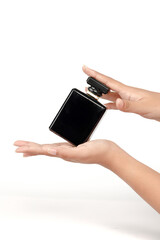 Elegant black perfume bottle held by hands on white background, perfect for beauty and luxury product concepts.