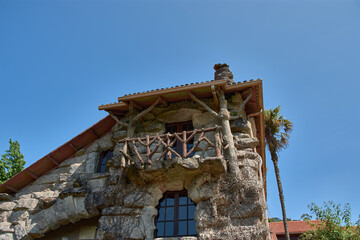 Rustic stone facade of the Monte Aloia Park Interpretation Center under a clear sky and bright light